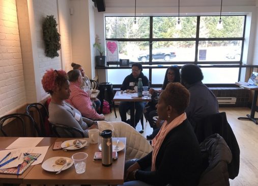 a group of women sit around a table in discussion
